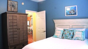 Ein Schlafzimmer mit Bett, Kleiderschrank, Tür und einer Wand mit Uhr und einem gerahmten Bild.