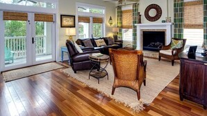 A spacious living room with a fireplace, leather sofa, and wicker chairs. - 5-bedroom Home just 4.5 min walk to Dedicated Private Beach & 2 community pools (Santa Rosa Beach)