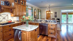 A spacious kitchen with wooden cabinets, a central island, and a dining area with a chandelier. - 5-bedroom Home just 4.5 min walk to Dedicated Private Beach & 2 community pools (Santa Rosa Beach)