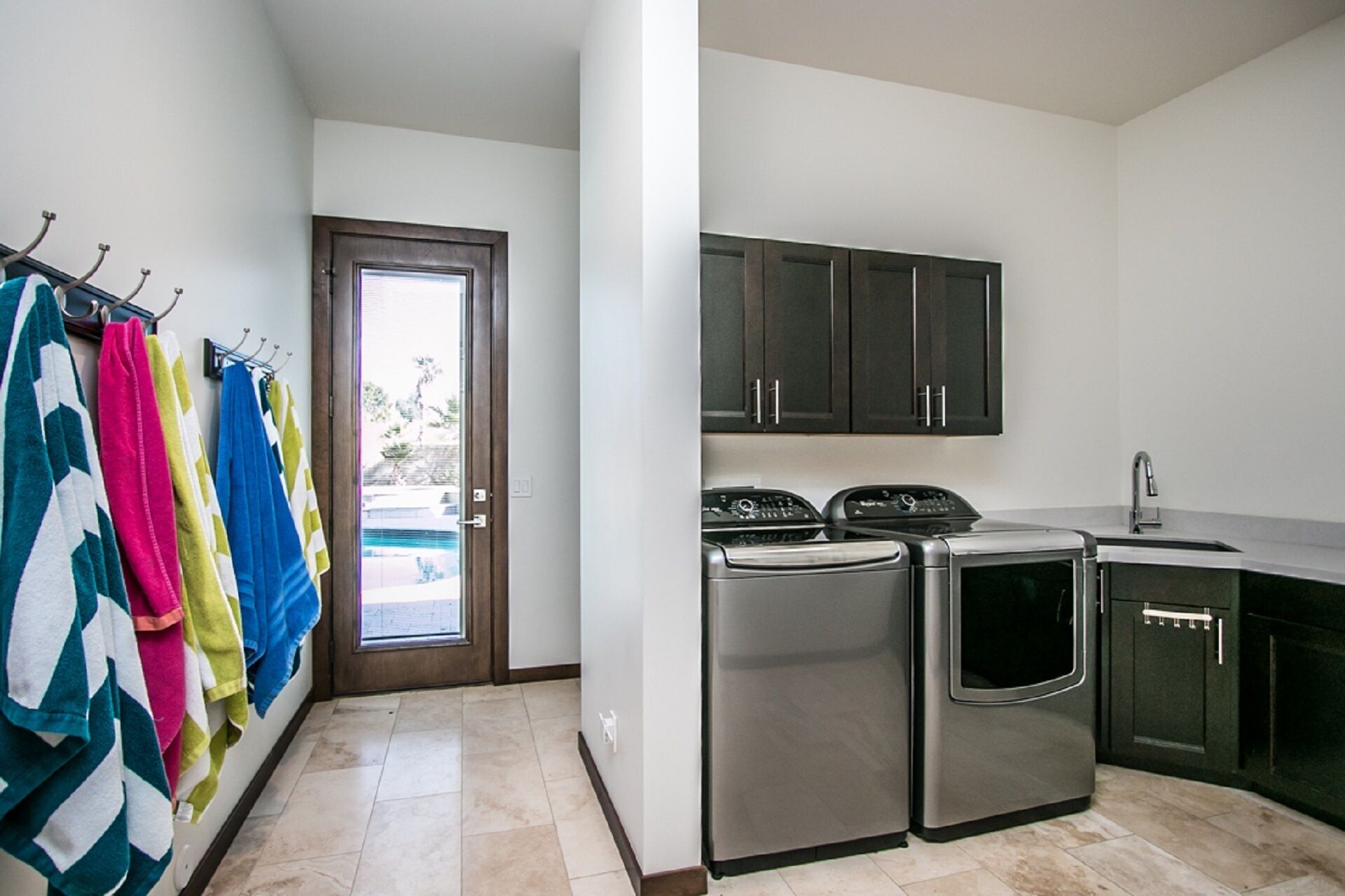 A compact kitchen with stainless steel appliances, dark cabinets, and a tiled floor.