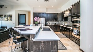 A modern kitchen with dark cabinets, stainless steel appliances, and a central island with bar stools.