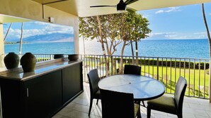 A balcony with a view of the sea, a ceiling fan, and a table with chairs. - Royal Mauian Oceanfront, Fabulous View!   (Kihei)