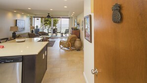 A modern kitchen with a dishwasher, a dining area with a table and chairs, and a living room with a sofa and a coffee table. - Royal Mauian Oceanfront, Fabulous View!   (Kihei)