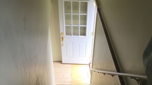 Una escalera de madera que lleva a una puerta blanca con un panel de vidrio.