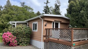 A single-story cabin with a wooden deck and a lattice fence.