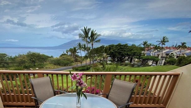 Ein Balkon mit Tisch und Stühlen, der einen herrlichen Blick auf das Meer und ein Gebirge bietet.