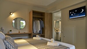 A bedroom with a bed, a wardrobe, a mirror, and a television displaying 'Good night'. - Maistrali Sea View Apartments (Hersonissos)