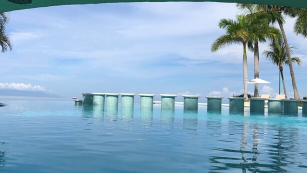 Une piscine dotée d’une plateforme flottante et bordée de palmiers.