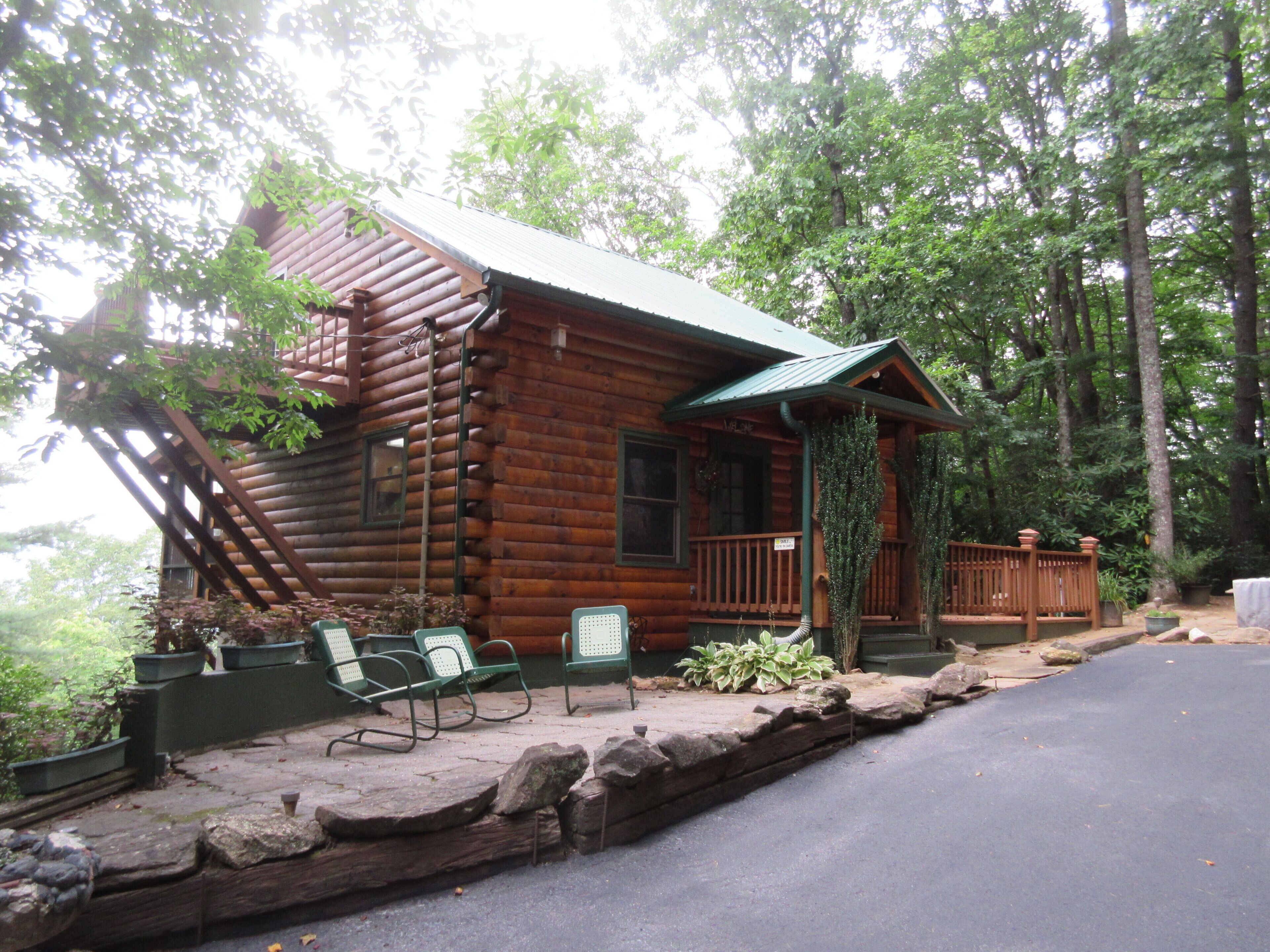 Eine rustikale Holzhütte mit Veranda, Sitzgelegenheiten im Freien und einer Steinschüttung.