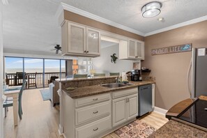 A kitchen with a large island, a refrigerator, and a view of the ocean.