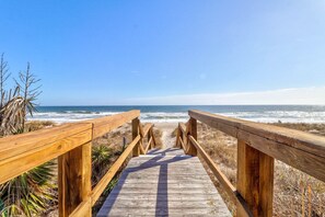 A wooden boardwalk leading to the beach with clear skies.