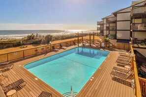 A pool area with a view of the beach and ocean.