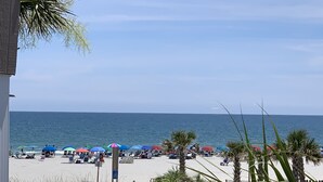En strandutsikt med parasoller, solstolar och en träbrygga.