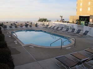 A swimming pool with lounge chairs and a white fence, overlooking a body of water. - Great condo east of Shore Drive.  (Myrtle Beach)