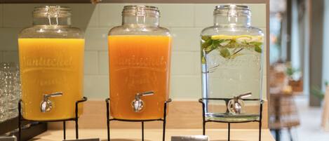 Three juice dispensers with labels on a countertop.