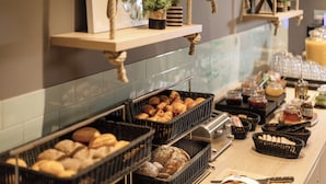 Un bufé con diversos alimentos y bebidas, entre ellos pan, pasteles y salsas.