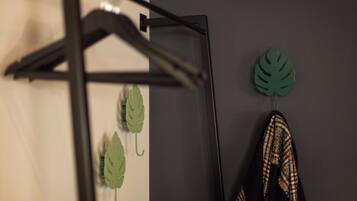 A black metal hanger with a green leaf decoration and a pair of plaid shoes against a grey wall.