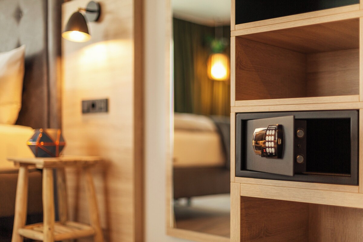 A wooden cabinet with a safe, a small stool, and a lamp.
