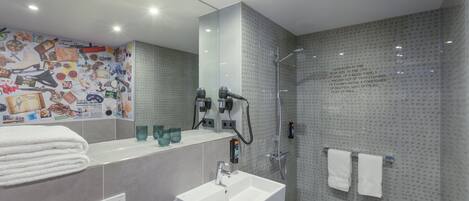 A modern bathroom with a large mirror, a sink, and a shower.