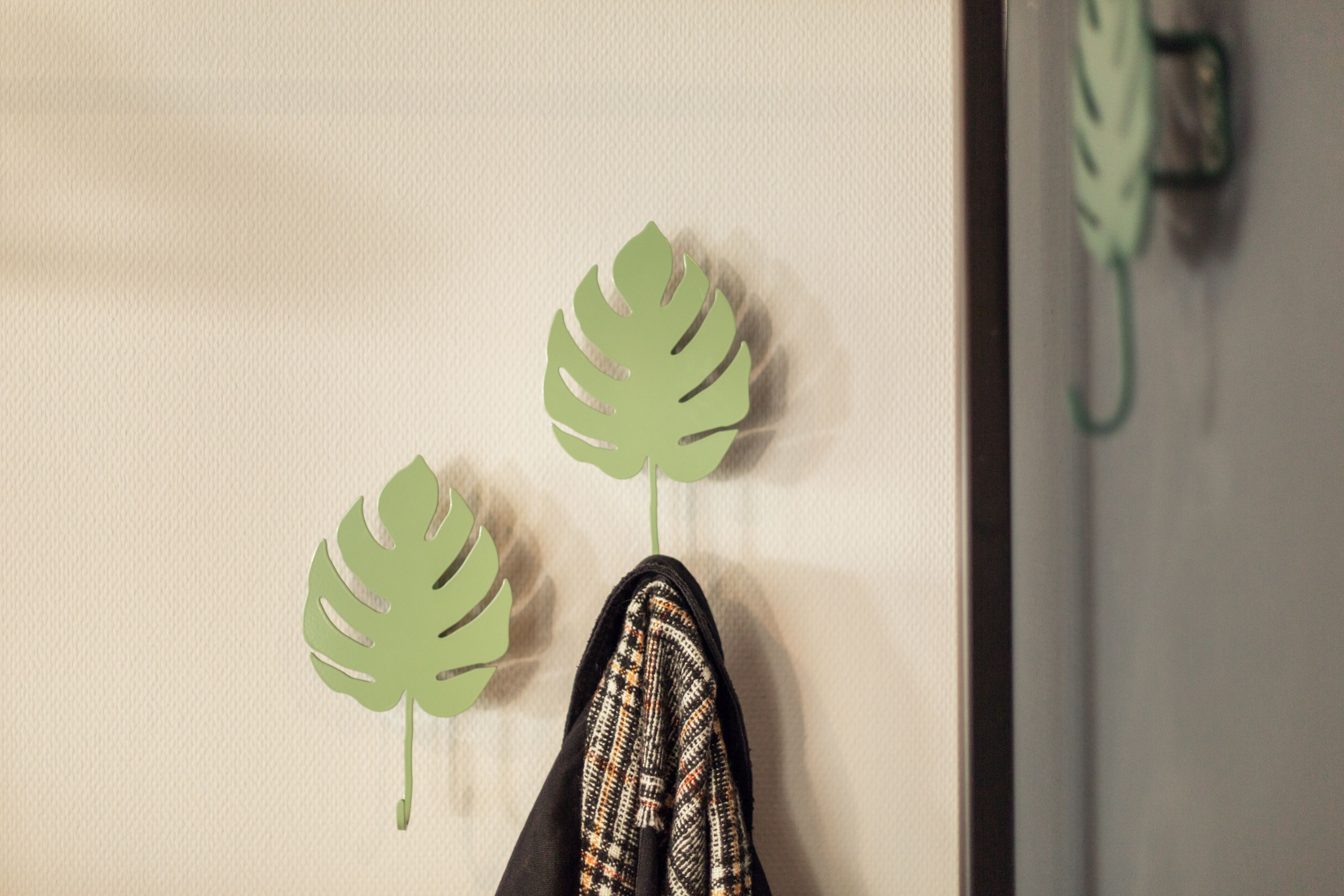 Une paire de chaussures à semelle à motifs, un mur à surface texturée et deux décorations en forme de feuilles vertes.