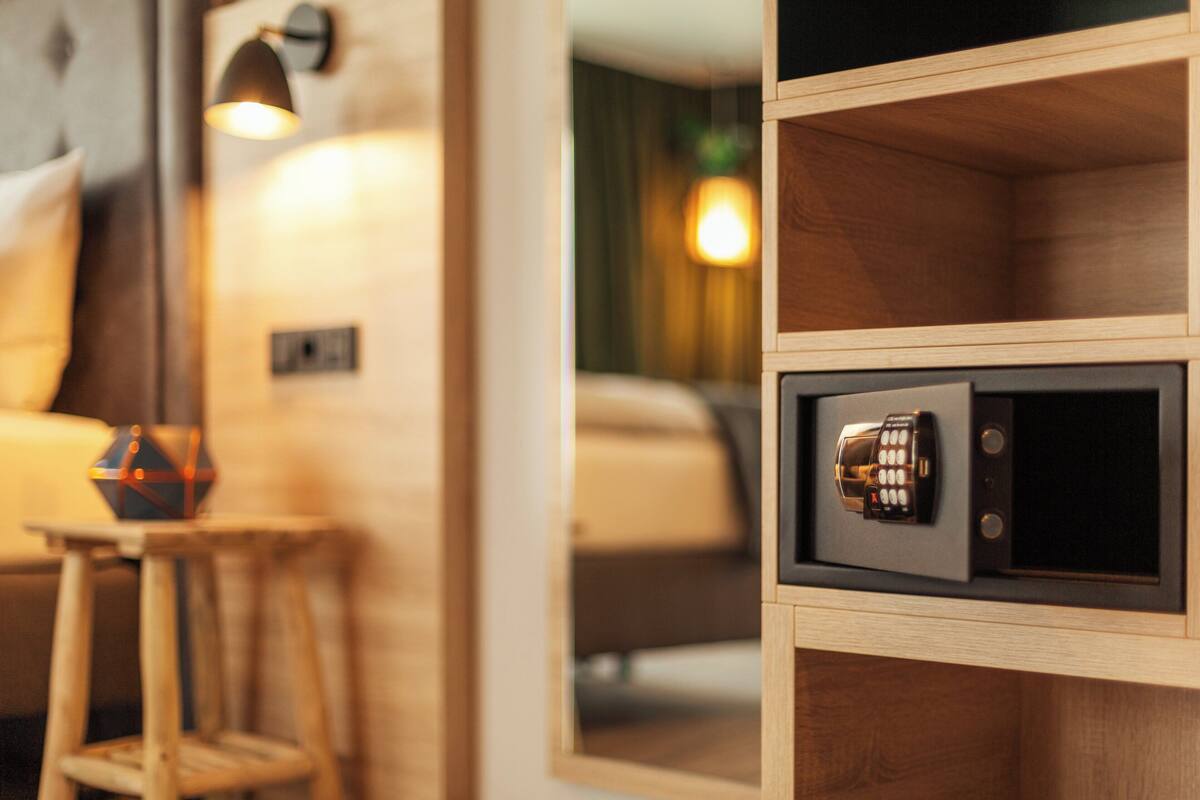 Een houten kast met een kluis, een klein krukje en een lamp.