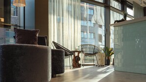 Un interior moderno con ventanas amplias, una zona de estar con sofá y sillones, y una encimera de cocina.
