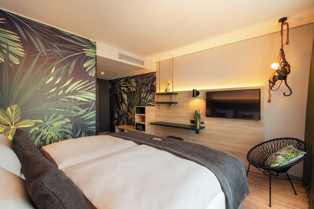 Een moderne slaapkamer met een bed, een stoel, een televisie en een muur met een plantenmuur.