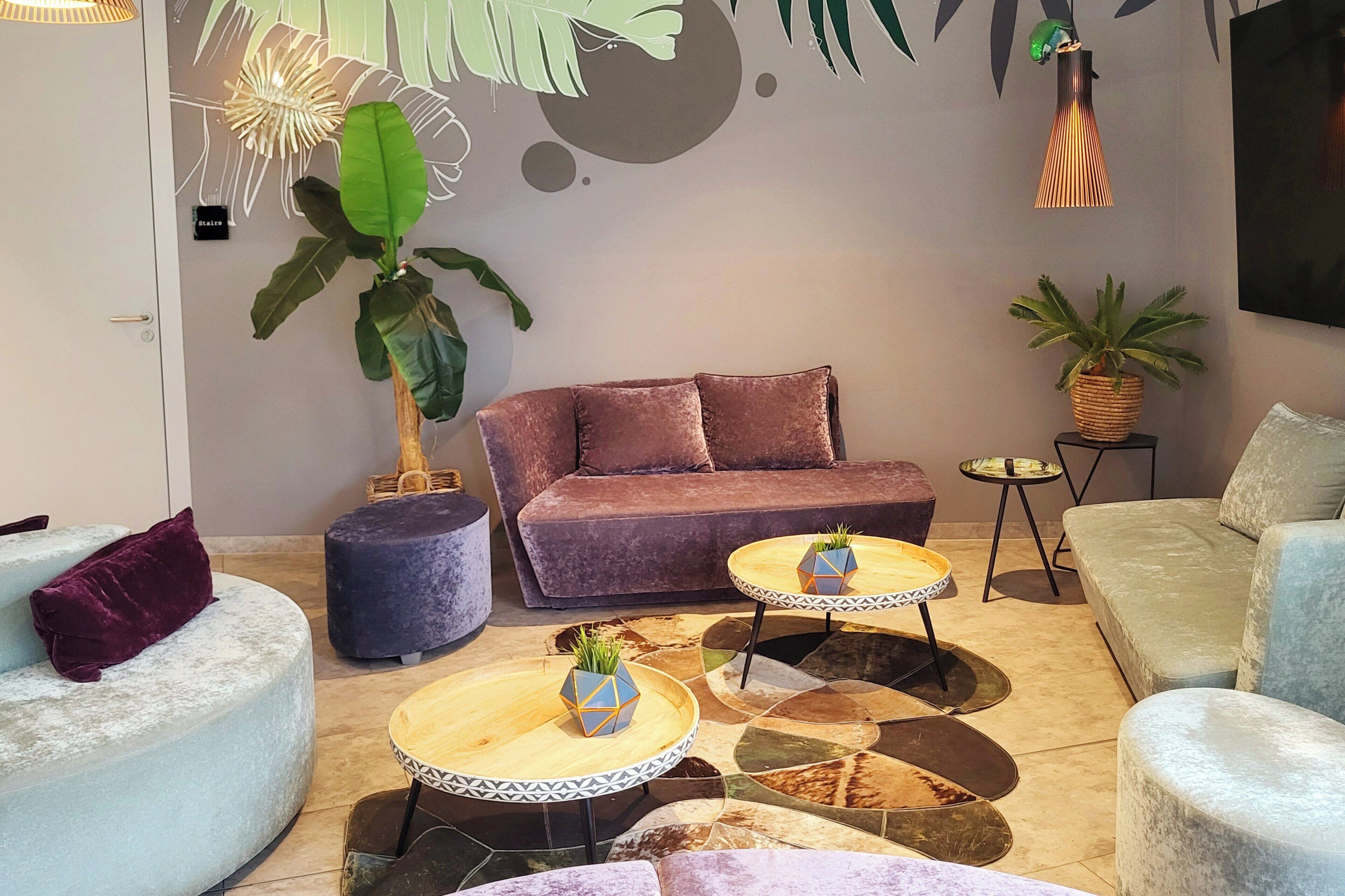 Una sala de estar moderna con un sofá, dos mesas redondas y una planta grande.