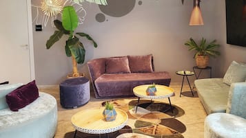 A modern living room with a sofa, two round tables, and a large plant.