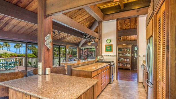 A spacious kitchen with wooden cabinetry, a granite countertop, and a view of the outdoors.