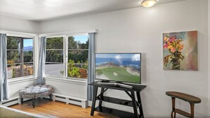 Ein Zimmer mit Fernseher, einer Bank und einem Gemälde an der Wand.