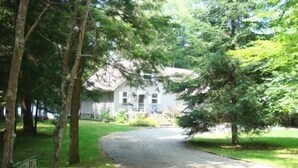 A residential driveway leading to a house surrounded by trees. - Camp Pinecone--Waterfront Home on Upper Saranac Lake (Saranac Lake)
