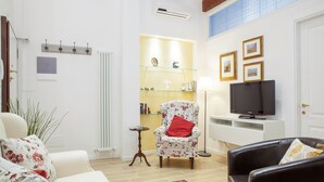 A living room with a sofa, a chair, a television, and a bookshelf. - Beautiful, Bright, Spacious in Historic Bologna, great atmosphere, renovated (Bologna)
