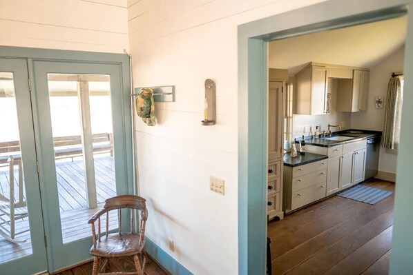 A kitchen with wooden cabinets, a countertop, and a view into the dining area. - StarHill Farms Ranch House (New Ulm)