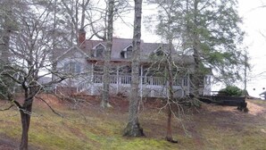 A house with a white fence, a red fire hydrant, and bare trees. - Charming Bear Paw Cabin with Spectacular View of Lake Hiwassee (Murphy)