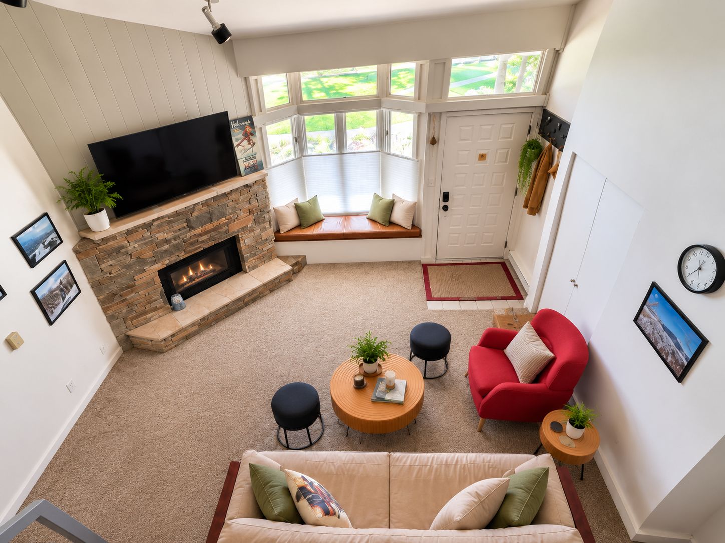 A living room with a stone fireplace, a red sofa, a beige couch, and a television.