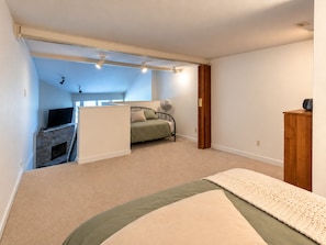 Ein Schlafzimmer mit einem Bett, einem Fernseher auf einem Schrank, einem Kamin und einem Holzschrank.