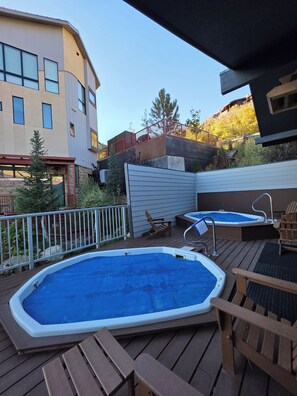 A backyard with a hot tub, wooden deck, and a fenced area.