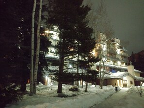 A multi-story building with snow-covered ground, surrounded by trees. - 300 steps to the slopes, Cozy Split-Level Loft, Fireplace, Hot Tubs, Free Bus (Steamboat Springs)