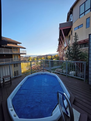 A swimming pool on a deck with a view of buildings and trees.