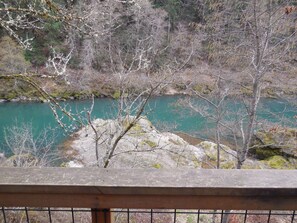 Una terraza de madera con vista a un río y árboles circundantes.