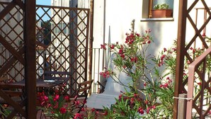 A courtyard with a tiled floor, potted plants, and a wooden gate. - B&B Il Mulino (Guardiagrele)