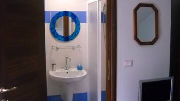 A bathroom with a sink, mirror, and a television on a stand.