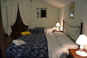 A hotel room with two beds, a nightstand with a lamp, a mirror, and a window with curtains. - B&B Il Mulino (Guardiagrele)