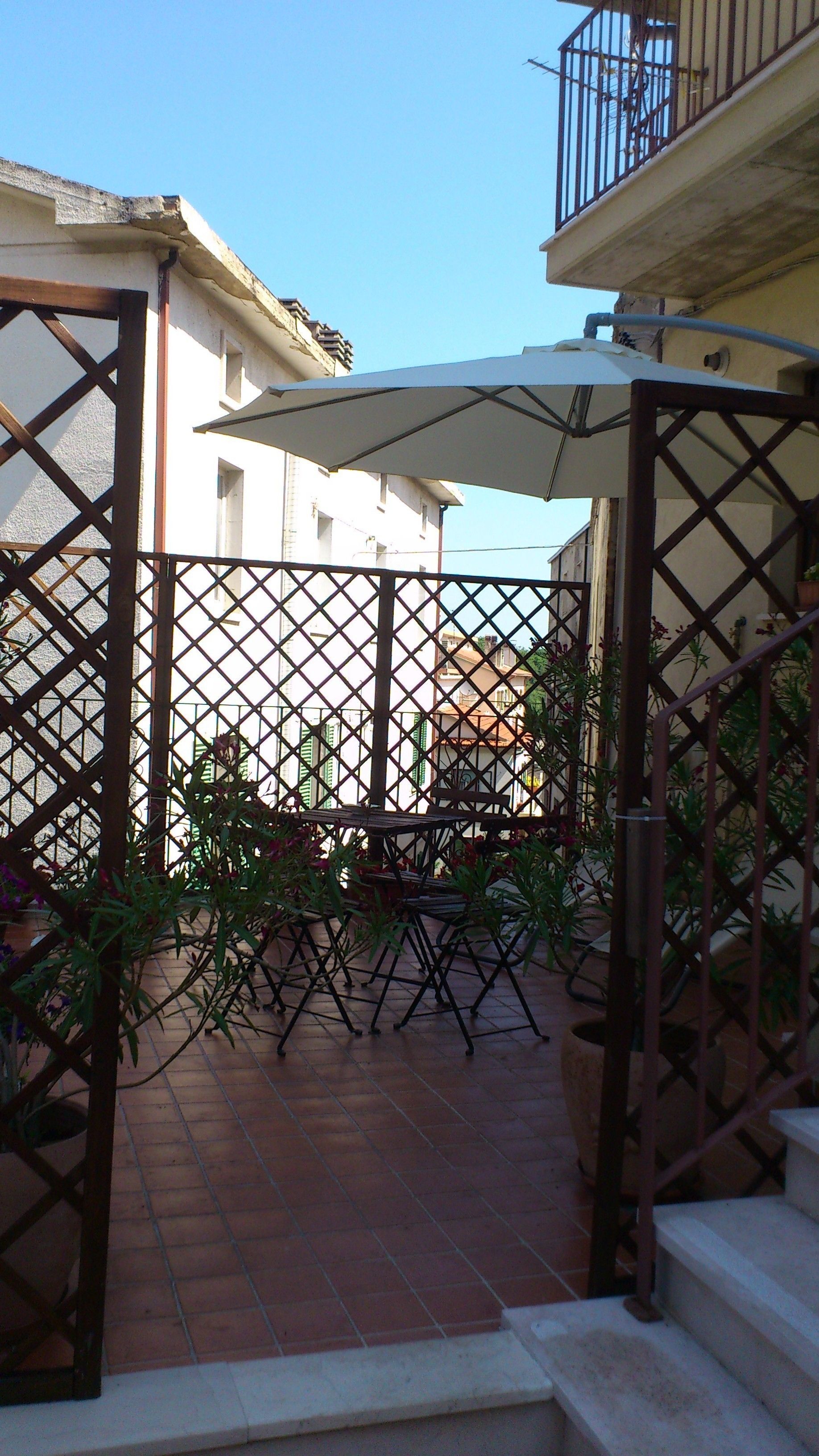 Un patio con cerramiento metálico, una mesa y plantas en macetas.