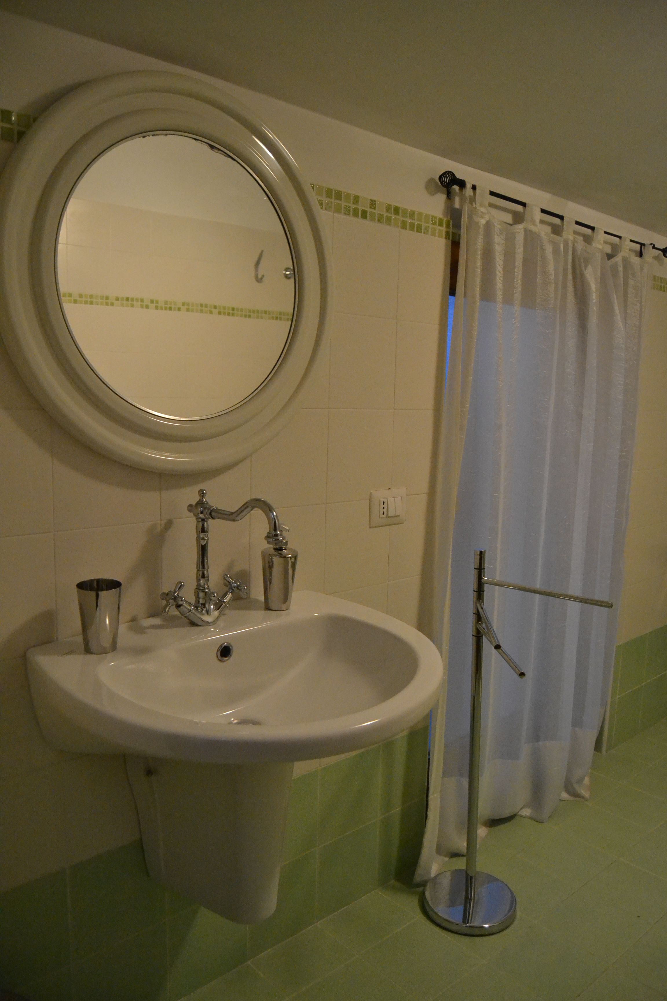 Une salle de bain avec un lavabo, un miroir et un rideau de douche.