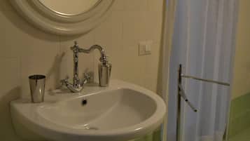 Une salle de bain avec un lavabo, un miroir et un rideau de douche.