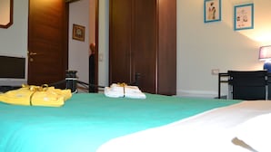 A hotel room with a bed, a desk, and a chair. There are towels and a suitcase on the bed. - B&B Il Mulino (Guardiagrele)