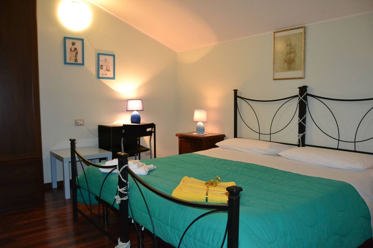 Une chambre bien rangée, avec un lit, des tables de chevet et une chaise.