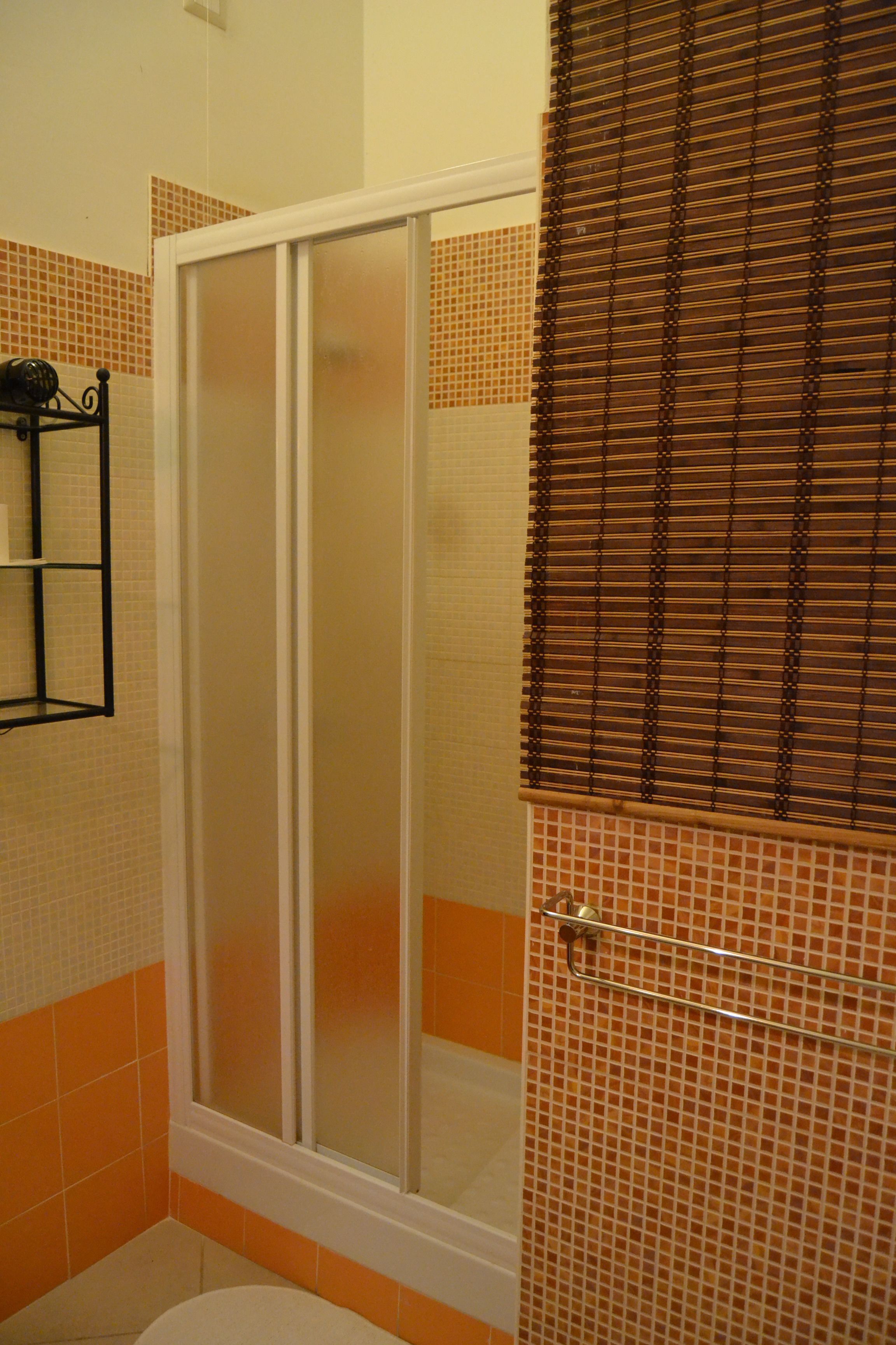 Une salle de bain avec une douche à parois de verre, des toilettes et un porte-serviettes.